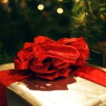 A gold wrapped present with a big red ribbon bow.