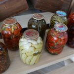Large canning jars filled with various fruits and vegetables.